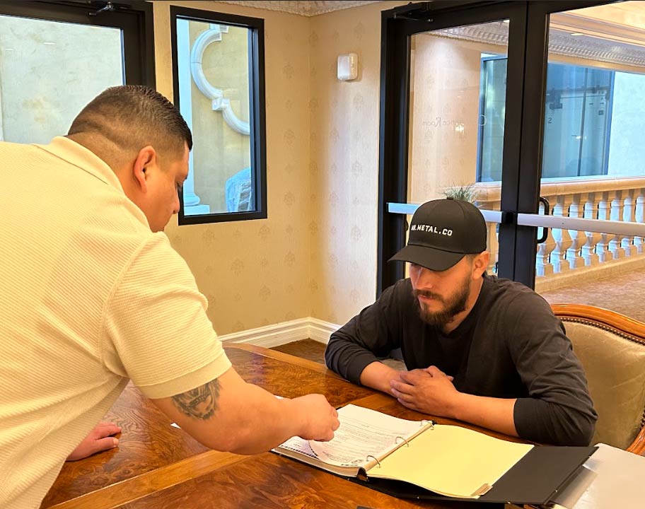 A Pro Business Solutions consultant reviewing a DBA registration binder with a client sitting at a wooden conference table during a professional consultation