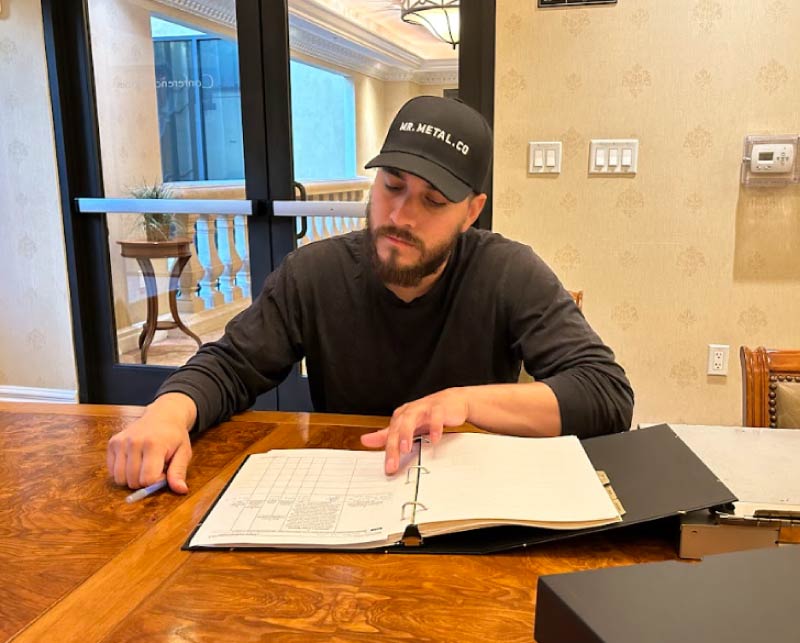 a focused business owner reviewing legal documentation and application paperwork in a binder for brand asset protection and trademark registration.