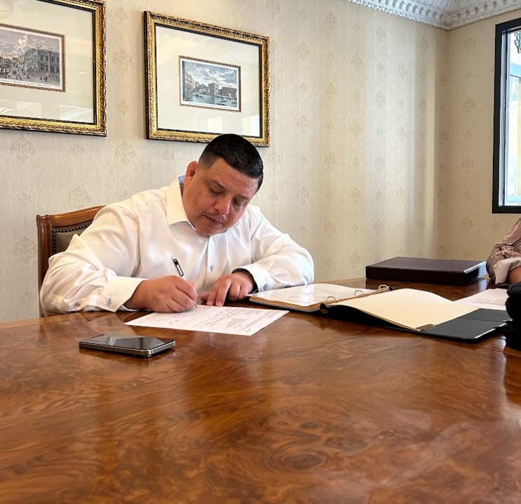 Business consultant Marcelo Umanzor Blanco reviewing and signing legal compliance documents at a conference desk
